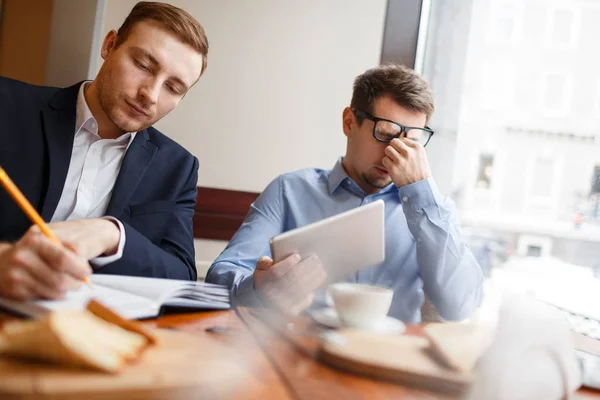 Contemporary businessmen working at meeting in cafe