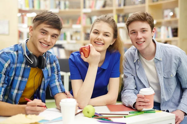 Retrato Tres Estudiantes Mirando Cámara Sonriendo Mientras Estudian Juntos Biblioteca — Foto de Stock