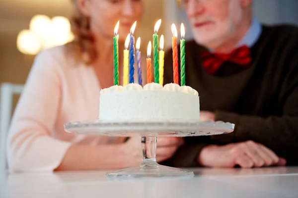 特写镜头的小奶油生日蛋糕与蜡烛的立场和尼斯的高级夫妇坐在表背景 — 图库照片