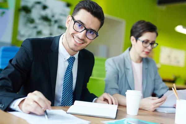 Joven Feliz Mirando Cámara Por Lugar Trabajo Mientras Lee Los — Foto de Stock