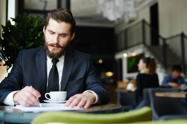紅茶のカップでカフェに応募者の履歴書を読んで深刻な雇用者 — ストック写真