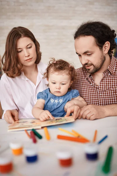 Семья с маленькой девочкой читают книгу вместе — стоковое фото