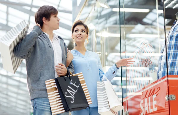 若い恋人 Paperbags で新しい服を議論するのには ウィンドウを表示します — ストック写真