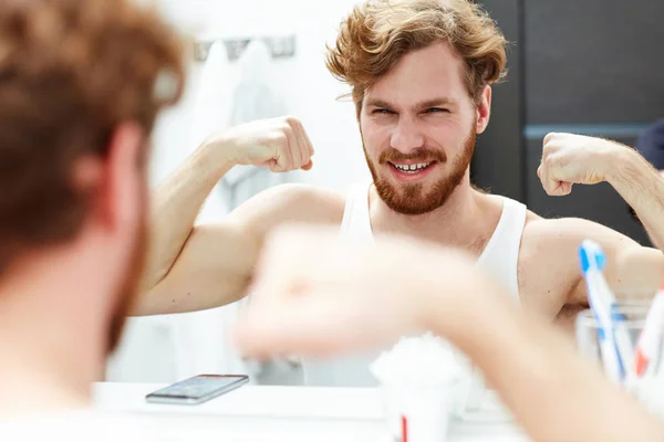 Homem Feliz Mostrando Seus Bíceps Frente Espelho — Fotografia de Stock