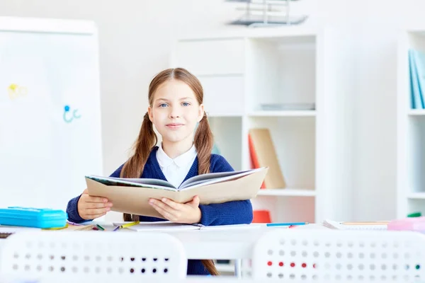 Nettes Schulmädchen Mit Offenem Lehrbuch Sitzt Ihrem Schreibtisch Klassenzimmer — Stockfoto