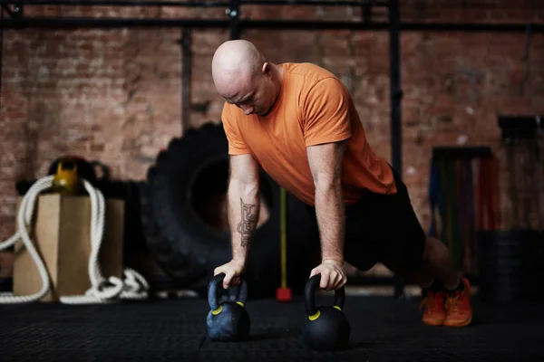 Tattooed Sporty Man Doing Push Ups Help Kettlebells While Having — Stock Photo, Image