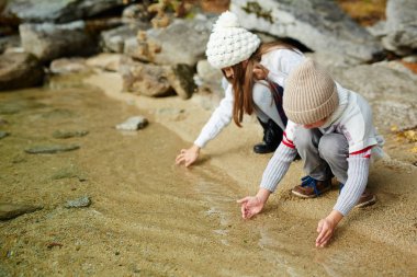 Çocuklar açık havada doğa içinde oyun: temiz su kum üzerinde sıcak sonbahar günü dokunmadan Gölü kıyısında oturan
