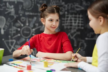 Sevimli küçük kız boyama resimleri okul blackboard karşı oturma sanat dersi sırasında arkadaşıyla portresi