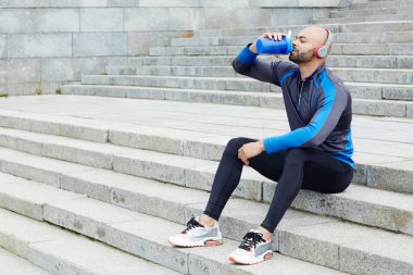 Susuz atlet merdiven üzerinde otururken taze su içme