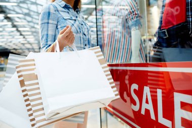 Kadın müşteri satış sırasında büyük modern merkezi ziyaret ederken paperbags holding