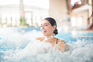 Kadın jakuzi spa yordamda sırasında sıcak su sıçramasına süre gülüyor heyecanlı