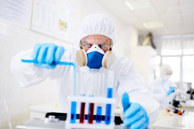 Çalışkan Viroloji araştırma bilim adamı giyen hazmat uygun virüs, iç arka plan üzerinde modern laboratuvar yüzleşmek için aşı geliştirme