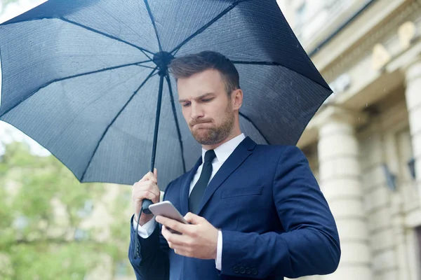 屋外の傘の下の Sms を読んで心配して実業家 — ストック写真