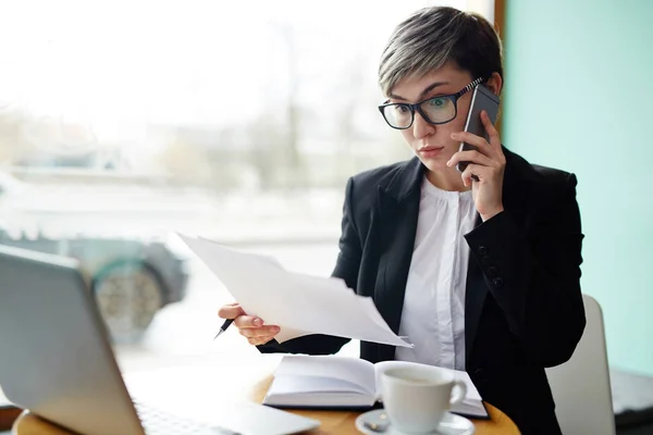 Verbaasd Vrouw Kijkt Document Tijdens Het Gesprek Cellphone — Stockfoto