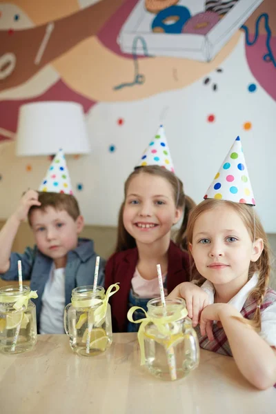在咖啡馆里有新鲜柠檬水的友好的孩子在生日帽 — 图库照片
