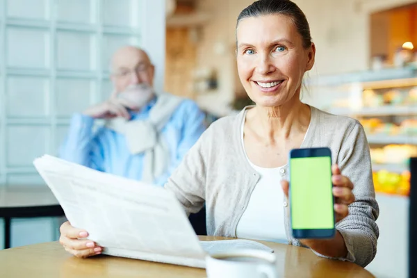 Wieku Kobieta Smartfonem Gazety Patrząc Kamery Mężem Tle — Zdjęcie stockowe