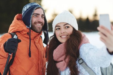 Selfie kış gününde park veya tatil yapma sırt çantaları ile mutlu kayakçı
