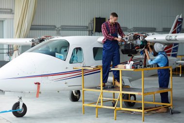 Hangarda uçak onarımı uçak servis mürettebat: iki genç mekaniği, erkek ve kadın, jet tamir uçak türbin