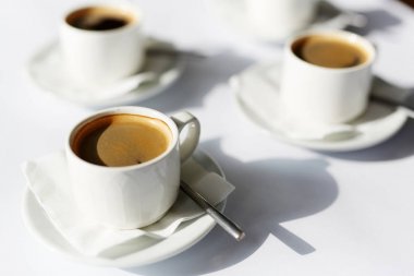 Üç porselen fincan siyah aromatik taze sıcak kahve beyaz kağıt peçete ve daireler