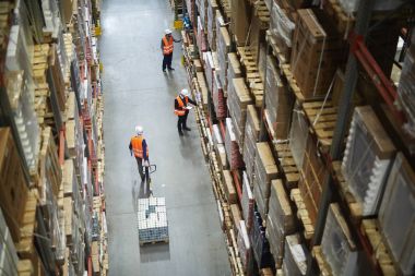 Ambarı işçilerin görünümünü eşya taşıma ve koridor uzun boylu raflar dolu kutu tam satırlar arasında stok sayım