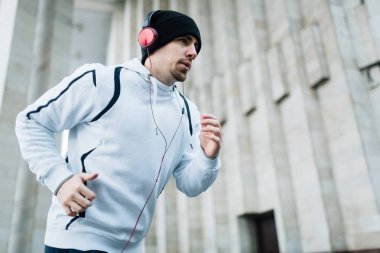Sportif adam stadyum üzerinde çalışan ve kulaklık favori müzik dinlemek