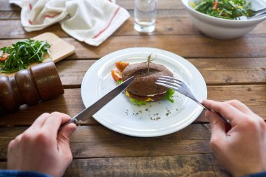 Çatal ve bıçak kesme sandviç plaka üzerinde insan eli