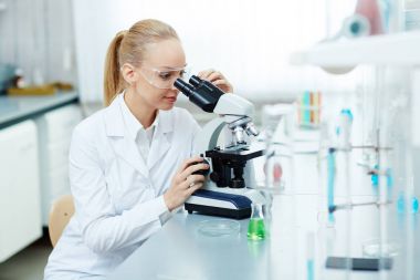 Modern laboratuvarda çalışan, kimyasal testler gerçekleştirme ve gülümseyen mikroskop kullanarak güzel bir kadın portresi