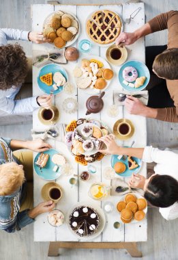 Şenlikli masaya oturan ve çay taze ev yapımı pasta ile sahip dört genç arkadaşlar