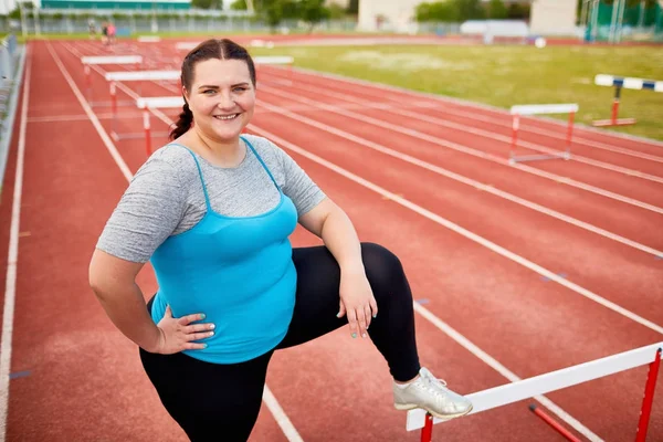 Úspěšná Obézní Žena Drží Jednu Nohu Překážku Přitom Stát Závodiště — Stock fotografie