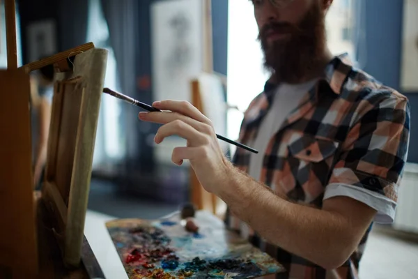 アーティストのスタジオでキャンバスに絵を描いている絵筆を保持しているエレガントな男性手のポートレート クローズ アップ — ストック写真