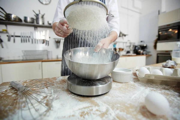 Pastry-chef sifting wheaten flour for dough