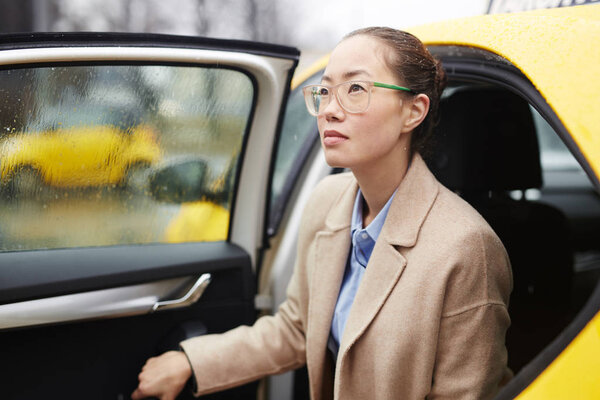 Modern woman in stylish clothes getting out of car