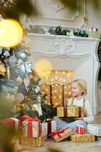 クリスマスの夜に自宅で暖炉のそばに座って装飾された Firtree で現在探している愛らしい子 — ストック写真