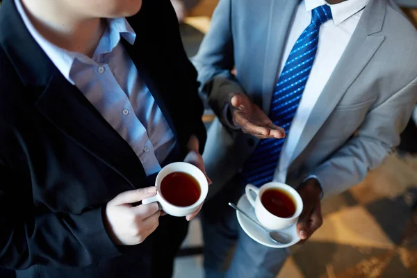 コーヒー ブレーク中に相互作用する つのビジネスの人々 の高角度 認識できないビジネスマン ジェスチャーと紅茶とカップを保持している同僚に話して — ストック写真