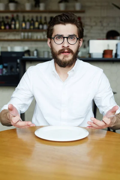 穿着白衬衣的年轻人坐在桌子旁 在咖啡馆里用空盘子 — 图库照片