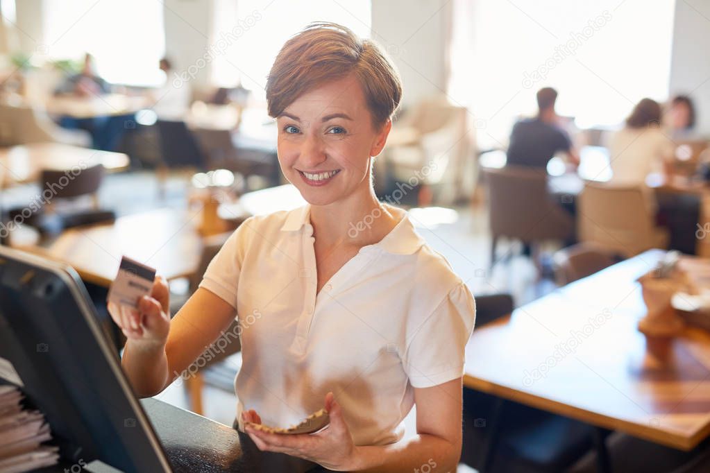 Successful staff of coffee-shop entering order of client in computer