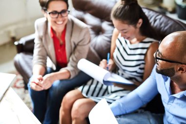 Çok etnik gruptan oluşan grup beyaz yakalı işçilerin rahat kanepe yüksek açılı görünüş modern ofis lobisinde otururken iddialı proje üzerinde birlikte çalışma