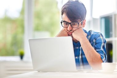 Laptop önünde oturan ve online bilgi için onun tez üzerinden seyir dalgın öğrenci