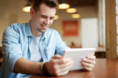 Video dijital tablet kafede kullanma ve sevinçle gülümseyen oyun oynarken modern genç adam portresi