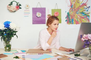 Elinde kalem tutan, sketchbook, renk renk örneği kitaplar ve diğer Kırtasiye Ofis Masası üzerinde yalan sırasında genç Illustrator yazılı e-posta ona müşteri konsantre