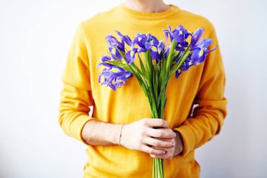 Buket çiçek beyaz duvara karşı ayakta ile poz tanınmaz halde genç adam portresi orta kesit