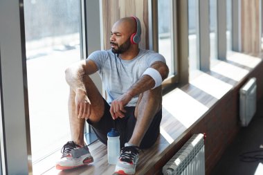 Pencere-pervazına üzerinde oturan ve pencereden bakarak genç sporcu