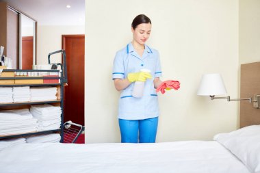 Otel hizmetçi lapmshade temizlemeden önce sünger üzerinde dezenfektan püskürtme