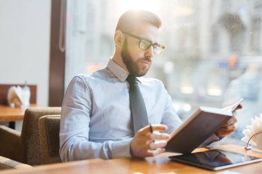 Ciddi işadamı kafede otururken onun notlar okuma