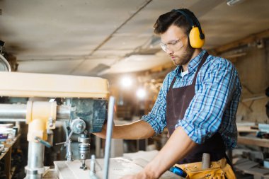 Kulak ve göz koruyucular kalıpçı geniş atölyede, dikey, bel ile çalışan genç woodworker yoğunlaştı