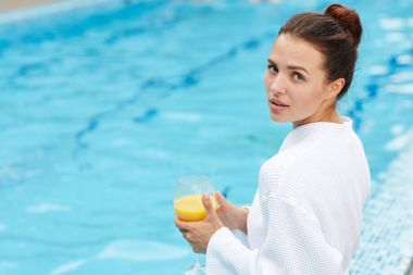 Bardak suyun kenarında oturan ve kameraya bakarak suyu ile genç esmer