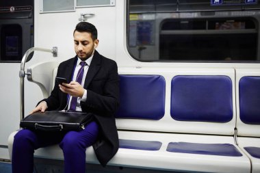 Müzik dinlemek için smartphone kullanarak metro treninin çalışmaya commuting Ortadoğu iş adamı portresi