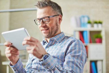 Kendi iş geliştirmek için iş webinar tablet izlerken dalmış gözlük pozitif orta yaşlı girişimci