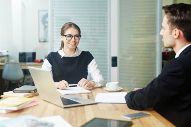 Tanınmayan meslektaşı, iç arka plan üzerinde geniş açık plan Office ile ortak proje tartışırken eğleniyor gözlük neşeli genç beyaz yakalı işçi