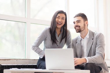 Dizüstü bilgisayarda çalışan ve uzak dişlek gülümsüyor, bel, dikey seyir oldukça Asya ofis çalışanı ve onun yakışıklı meslektaşım dağıttı